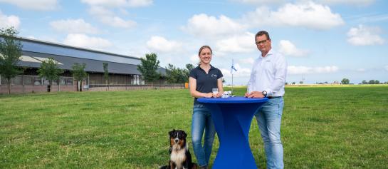 Melkveehoudster Anna Tjitske Wienia en DeLaval Solution Manager Sigmar Vosjan in een weiland aan een statafel met een glas melk. 
