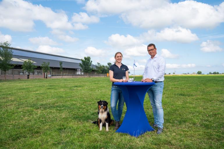Melkveehoudster Anna Tjitske Wienia en DeLaval Solution Manager Sigmar Vosjan in een weiland aan een statafel met een glas melk. 