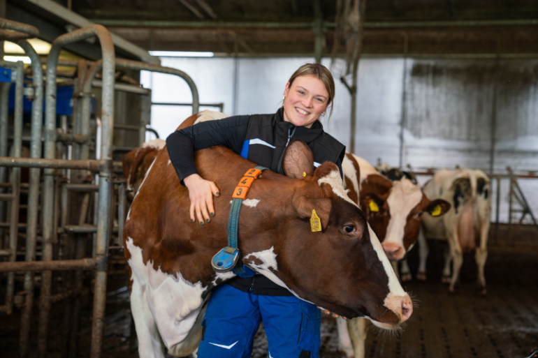 Melkveehouder Kim de Groot voor de DeLaval VMS V300 melkrobot met Flow-Responsive Milking knuffelend een melkkoe