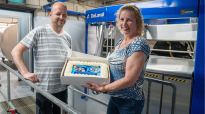 Joris en Mariska van Kempen voor de nieuwe DeLaval VMS V300 melkrobot met een taart in handen. Om te vieren dat er na 24 jaar een nieuwe robot in de stal staat. 