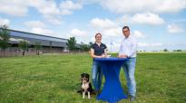 Melkveehoudster Anna Tjitske Wienia en DeLaval Solution Manager Sigmar Vosjan in een weiland aan een statafel met een glas melk. 